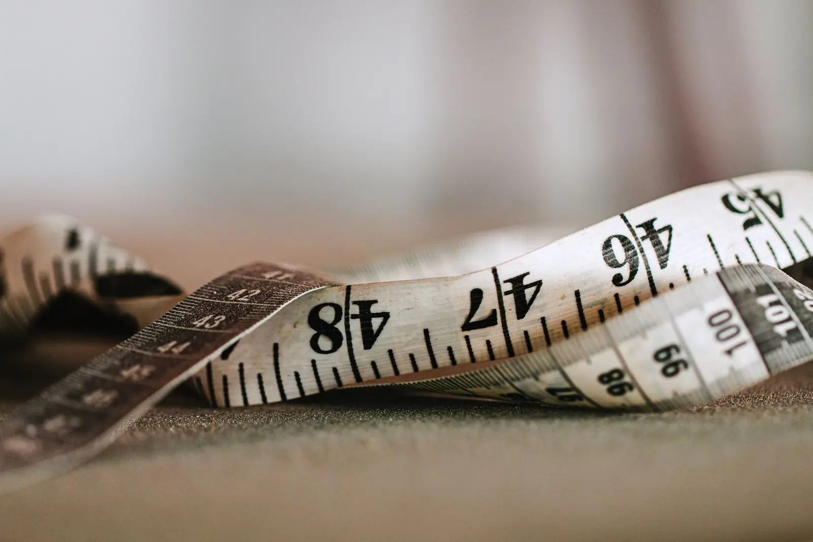 A cloth tape measure curled loosely on a table in soft, warm light