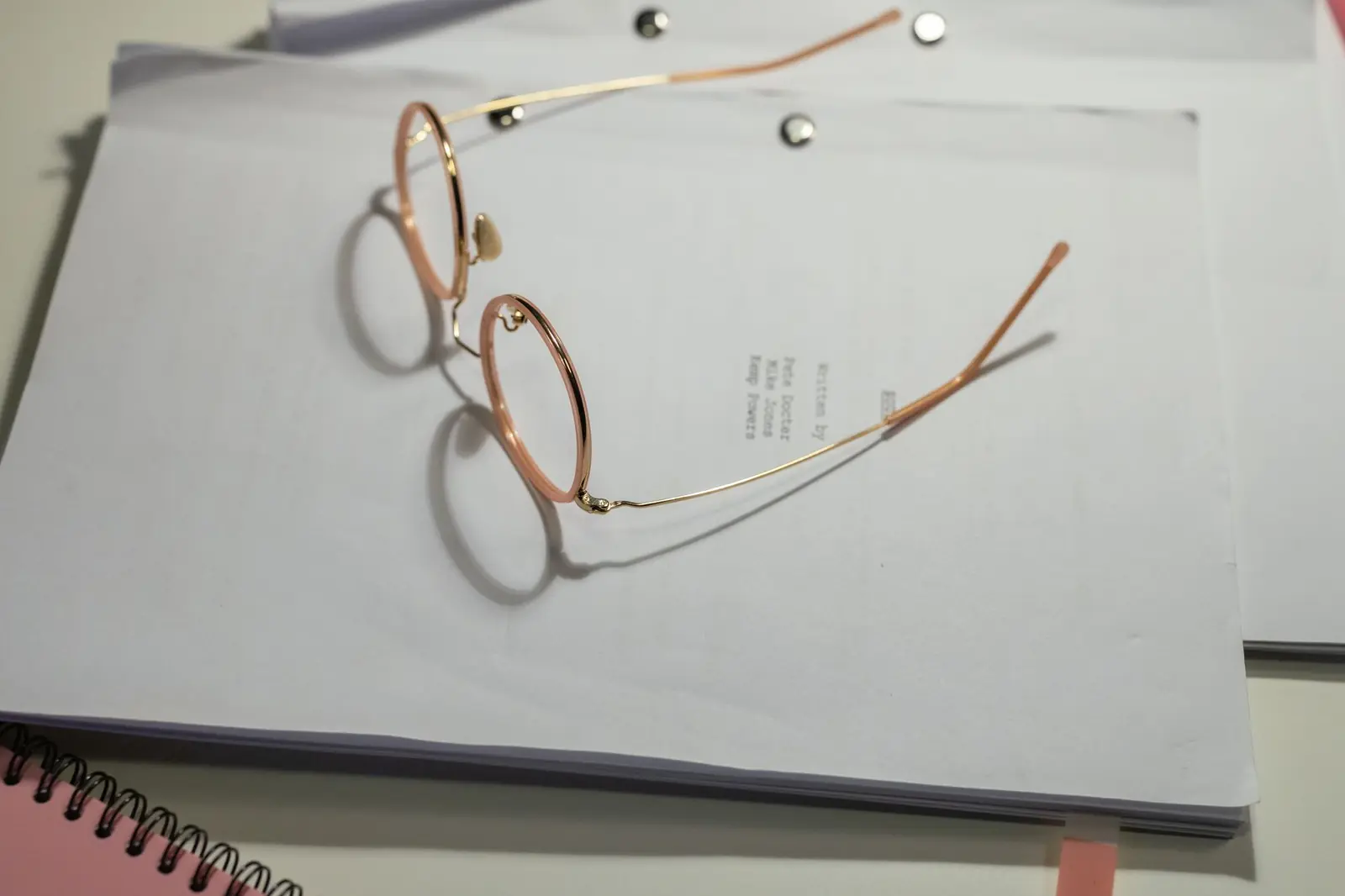 Gold-framed reading glasses resting on a stack of white printed documents