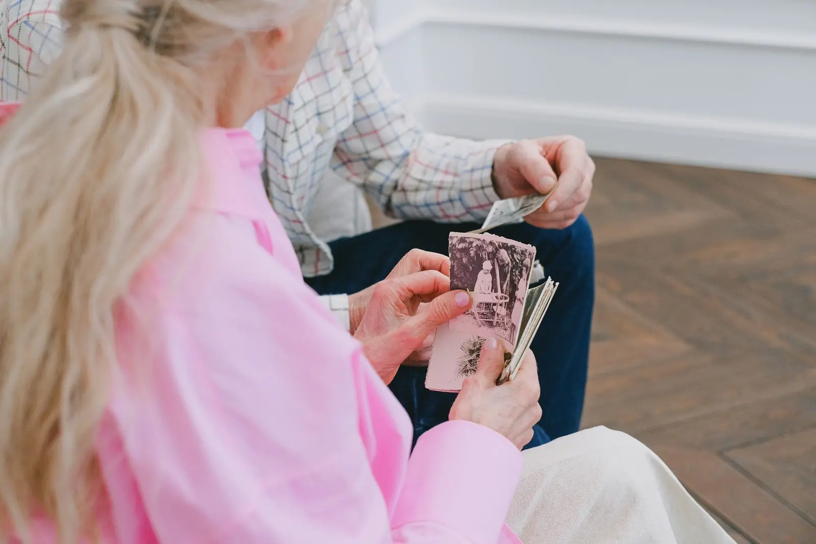 An older woman's hands holding old family photographs.