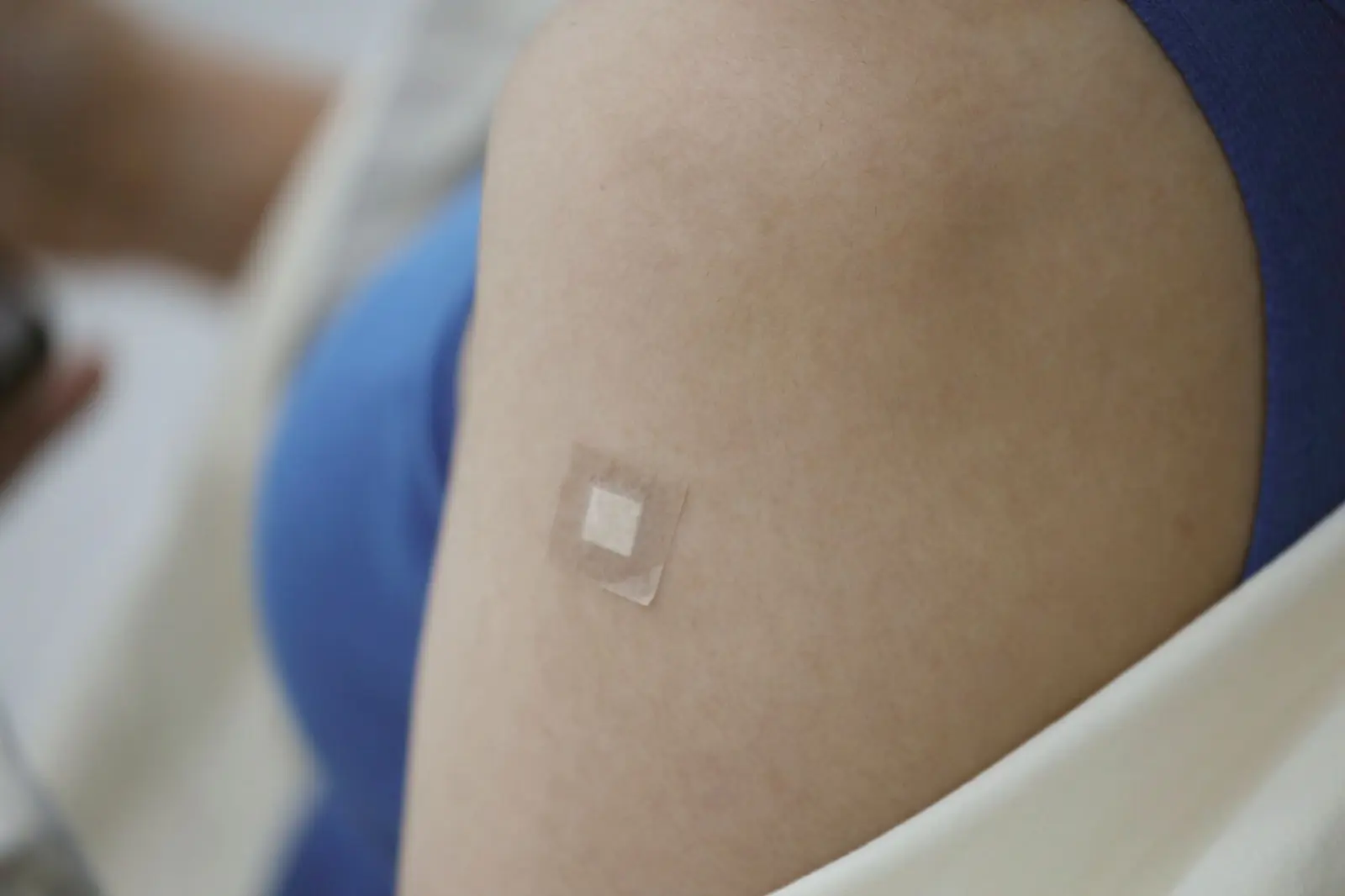 Close view of an upper arm with a small adhesive bandage after a vaccine shot