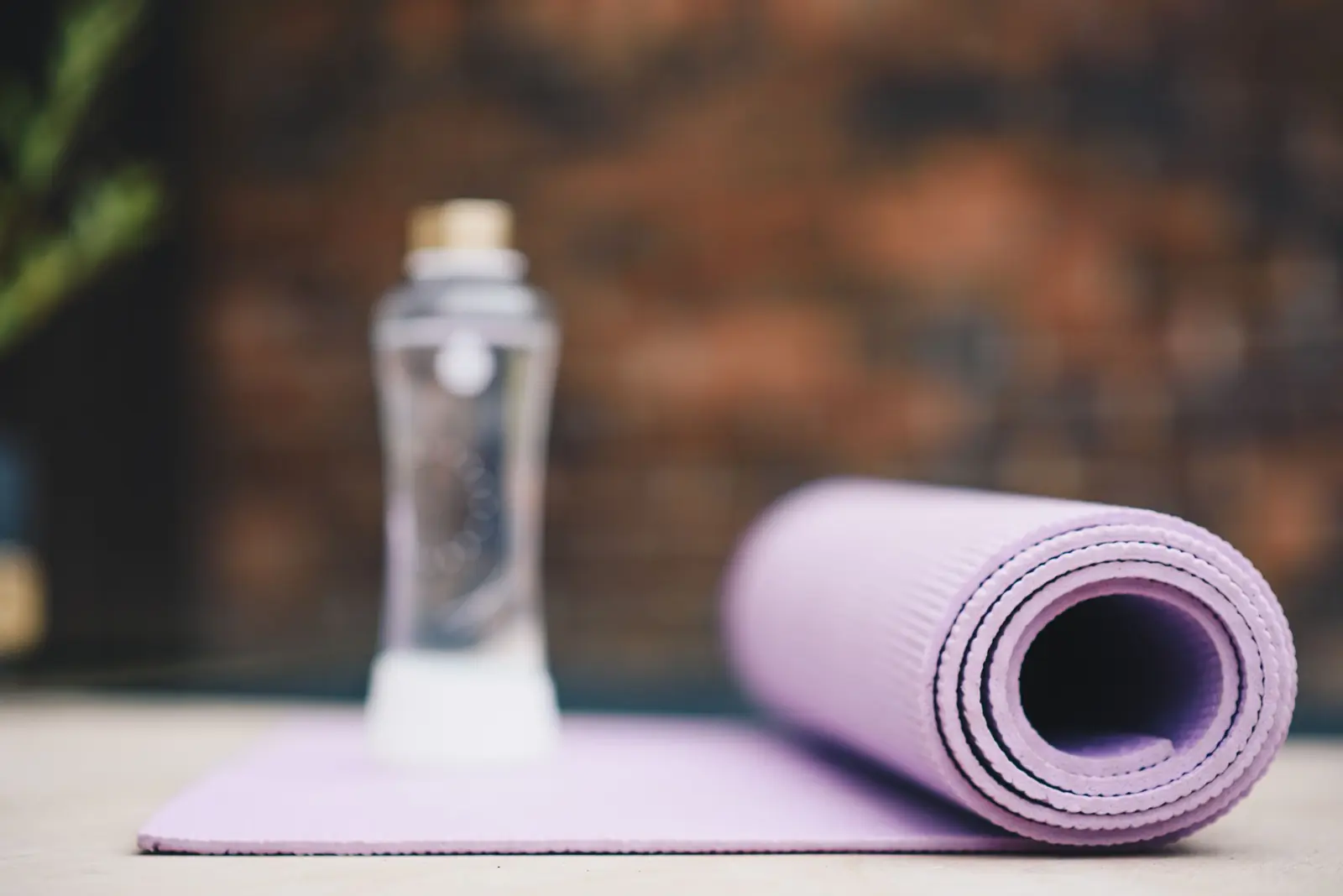 A rolled exercise mat and a water bottle in soft light.