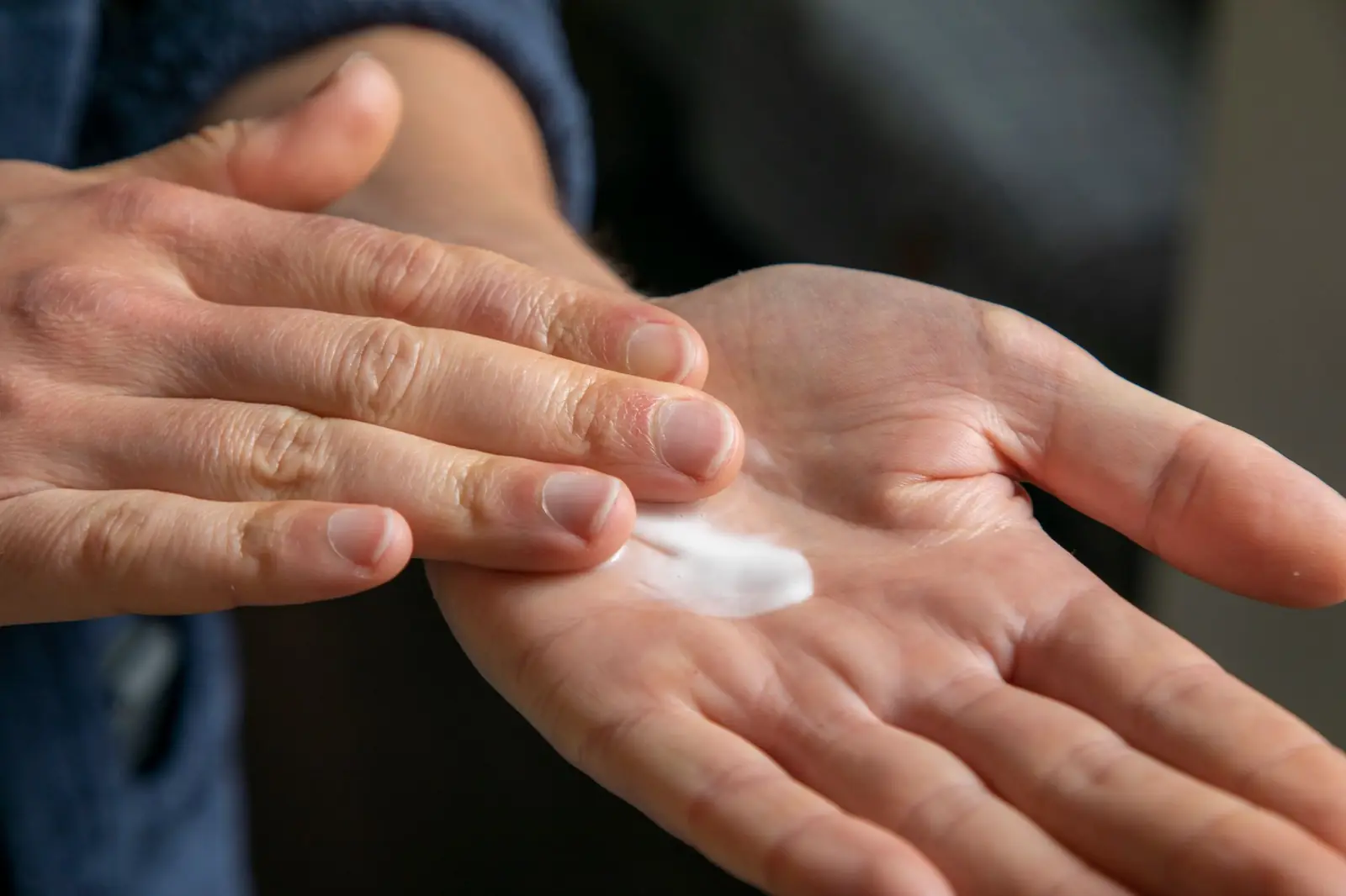 Close view of a person's hands rubbing a dab of white lotion into one palm