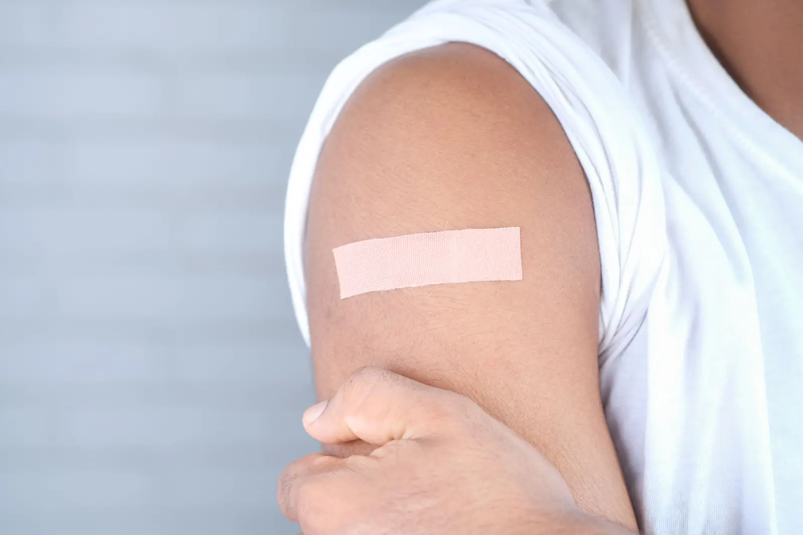 Close-up of an upper arm with a small adhesive bandage after a vaccination