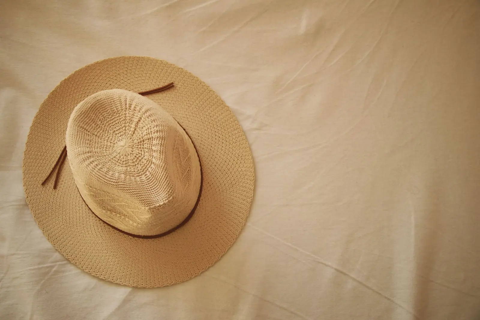 A woven straw sun hat resting on beige linen.